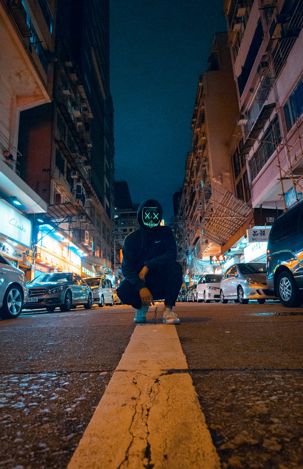 man wearing black hoodie knee on road with mask