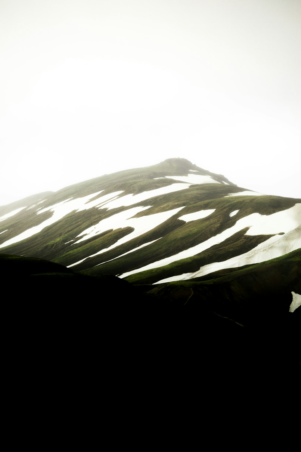 Montaña verde y blanca bajo el cielo blanco