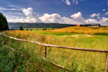 Traditional rural landscape with green fields and wooden fences maintained by the community.