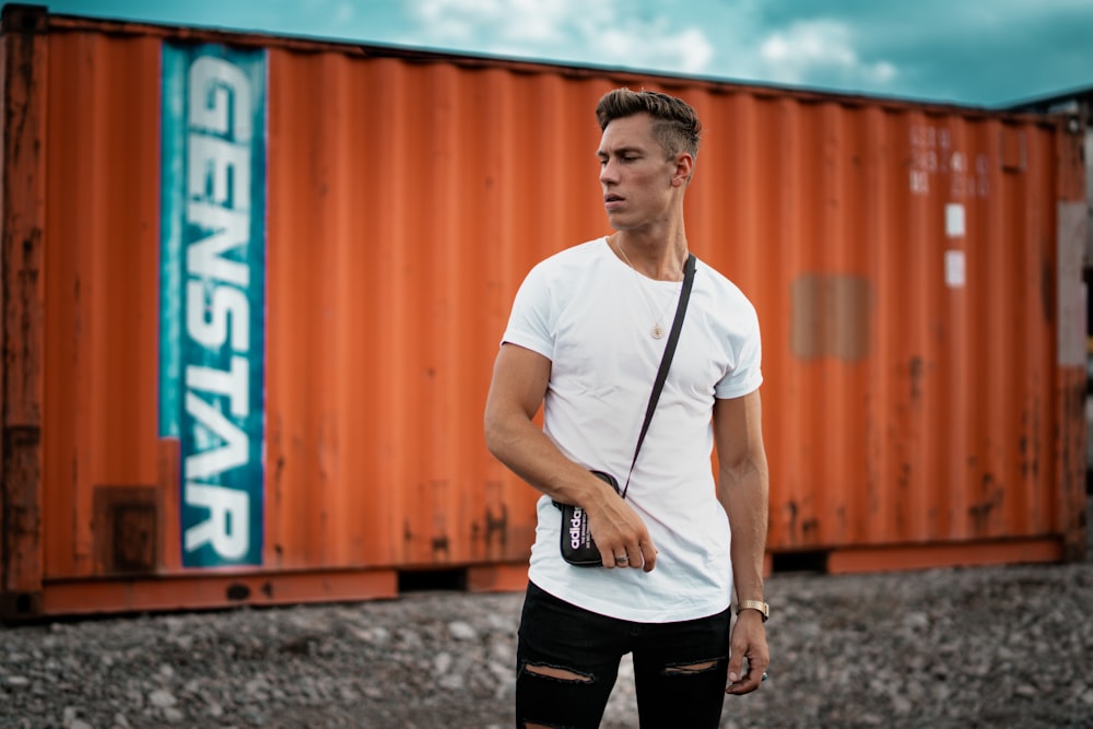 Homme portant un t-shirt blanc près d’un conteneur intermodal orange