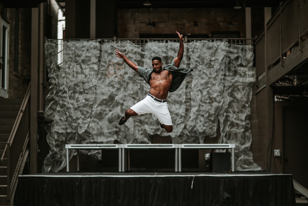 man raising his both hands while on air in front of stage