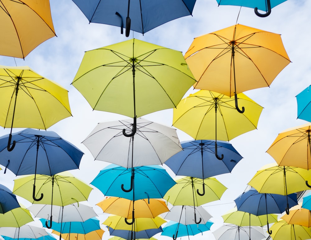 lote de paraguas de colores variados bajo nubes blancas durante el día