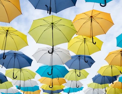 assorted-color umbrella lot under white clouds at daytime