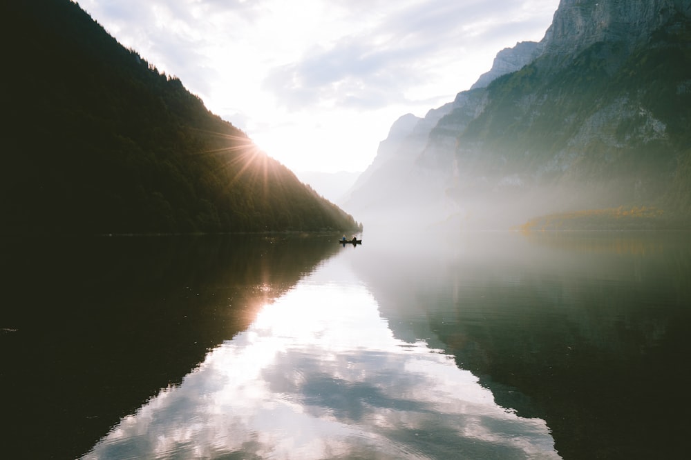 silhouette photo of mountain near lake at daytime