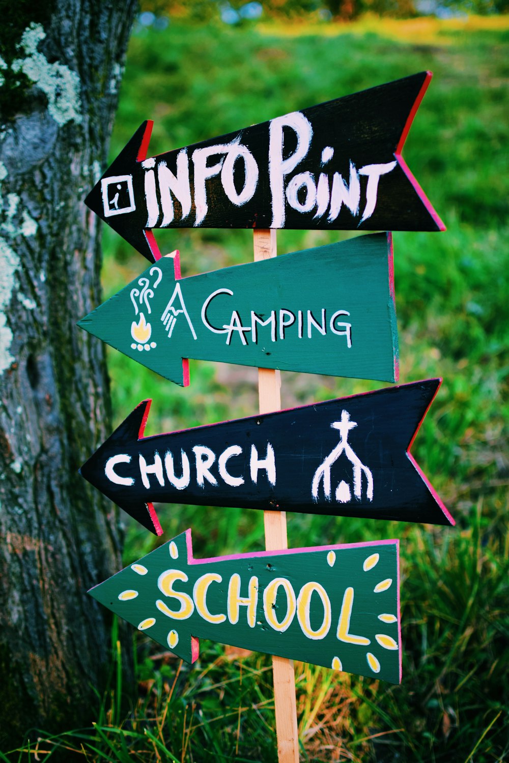 fotografia a fuoco selettivo della segnaletica di Info point, campeggio, chiesa e scuola a sinistra