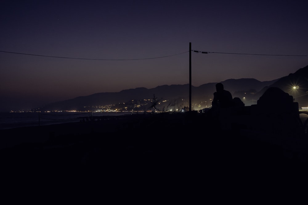 a couple of people sitting on a bench at night