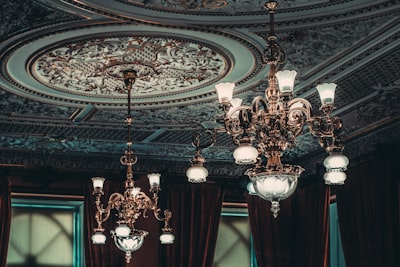 two gold-colored chandeliers on ceiling inside room fancy teams background