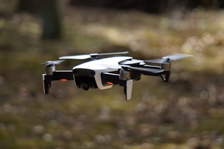 white and black quadcopter hovering on grass