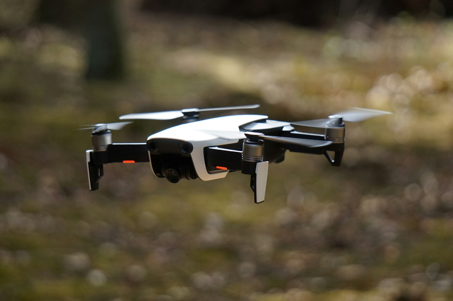 white and black quadcopter hovering on grass