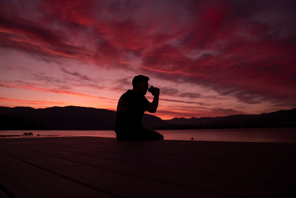 man sitting on dock during golden hour