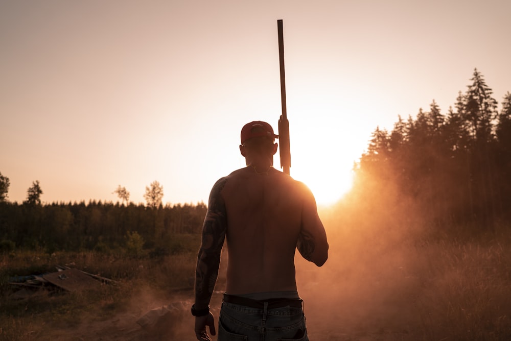 Hombre en topless sosteniendo una escopeta
