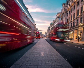 timelapse photography of double decker bus on road between buildings