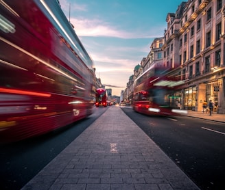timelapse photography of double decker bus on road between buildings