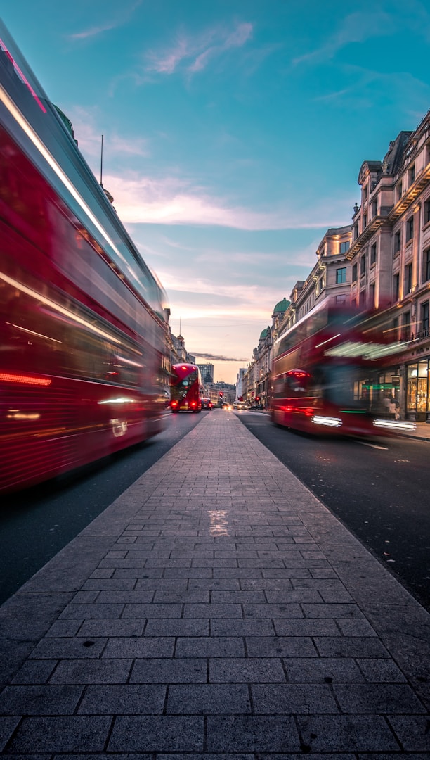 timelapse photography of double decker bus on road between buildings