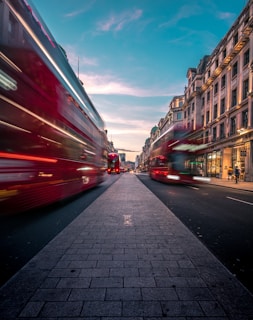 timelapse photography of double decker bus on road between buildings