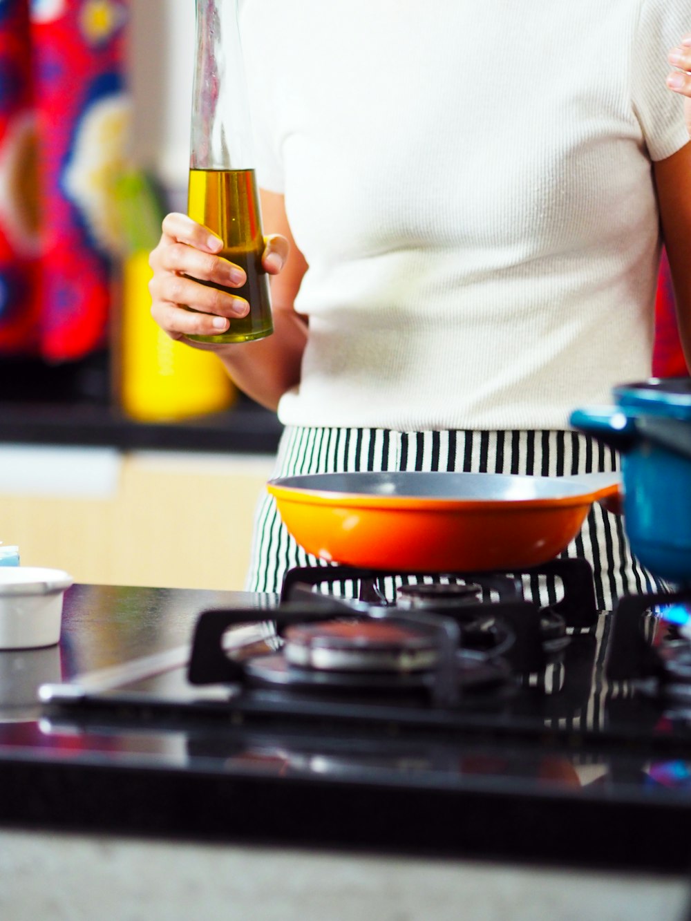 personne tenant une bouteille d’huile près d’une cuisinière à gaz