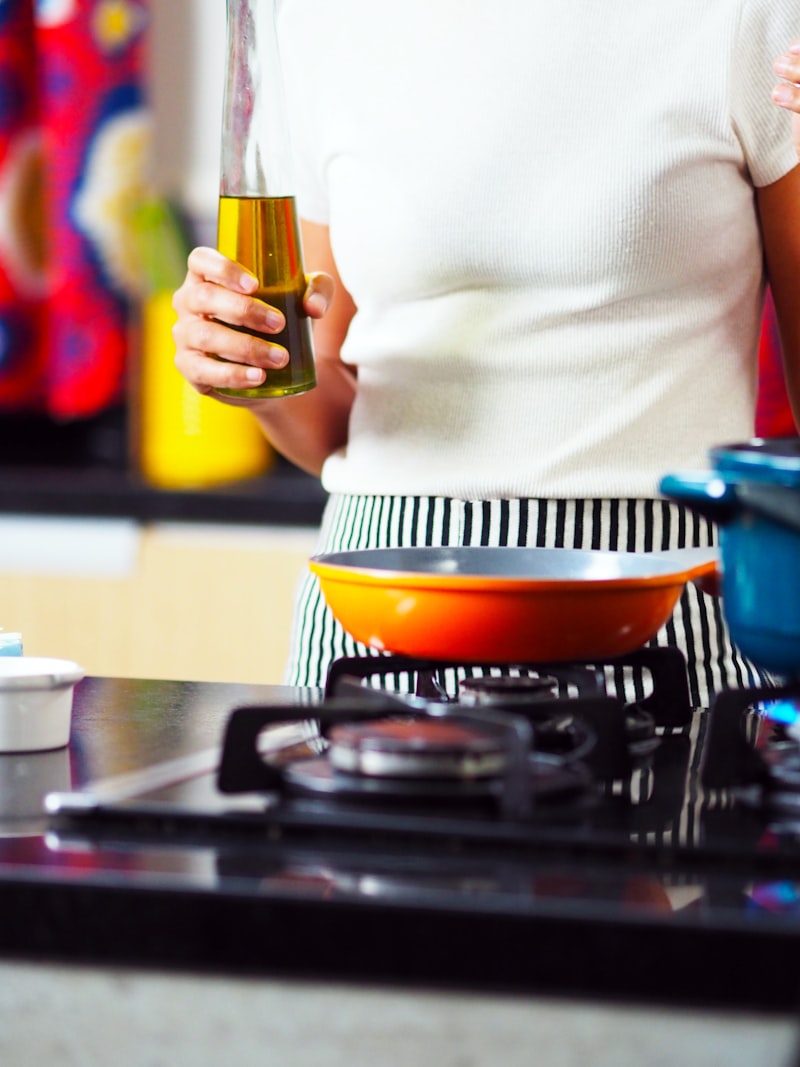 Senior woman cooking with healthy oil at a stove, making a heart-healthy meal