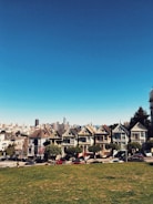 cars parked on sidewalk beside houses under clear blue sky