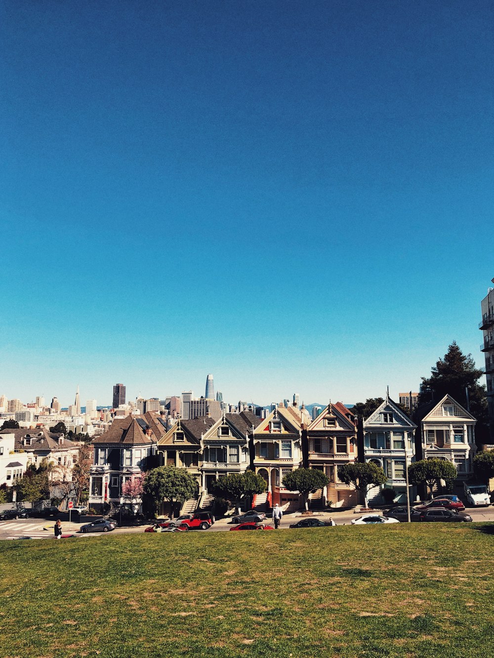 cars parked on sidewalk beside houses under clear blue sky