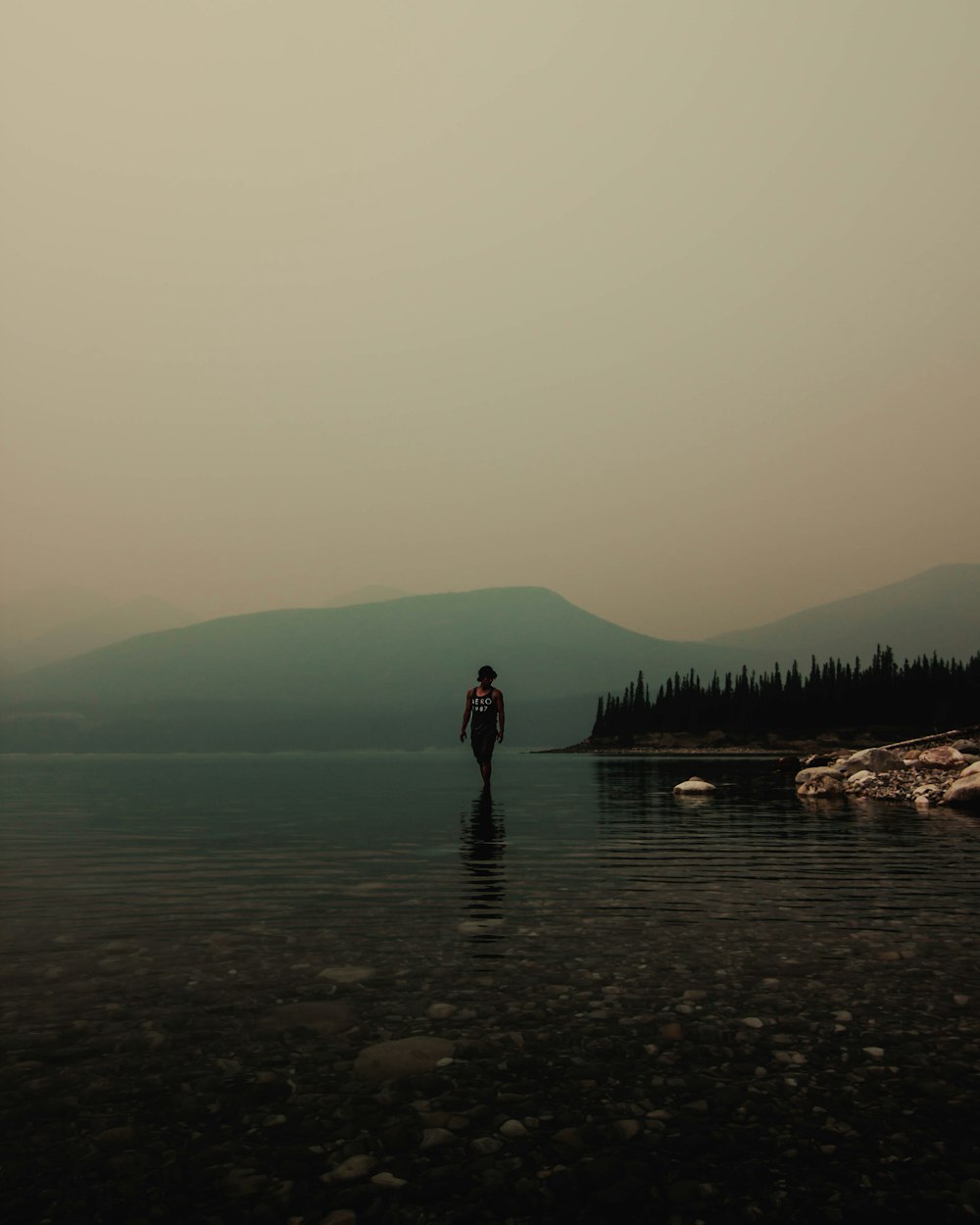 man standing on body of water and view of mountains