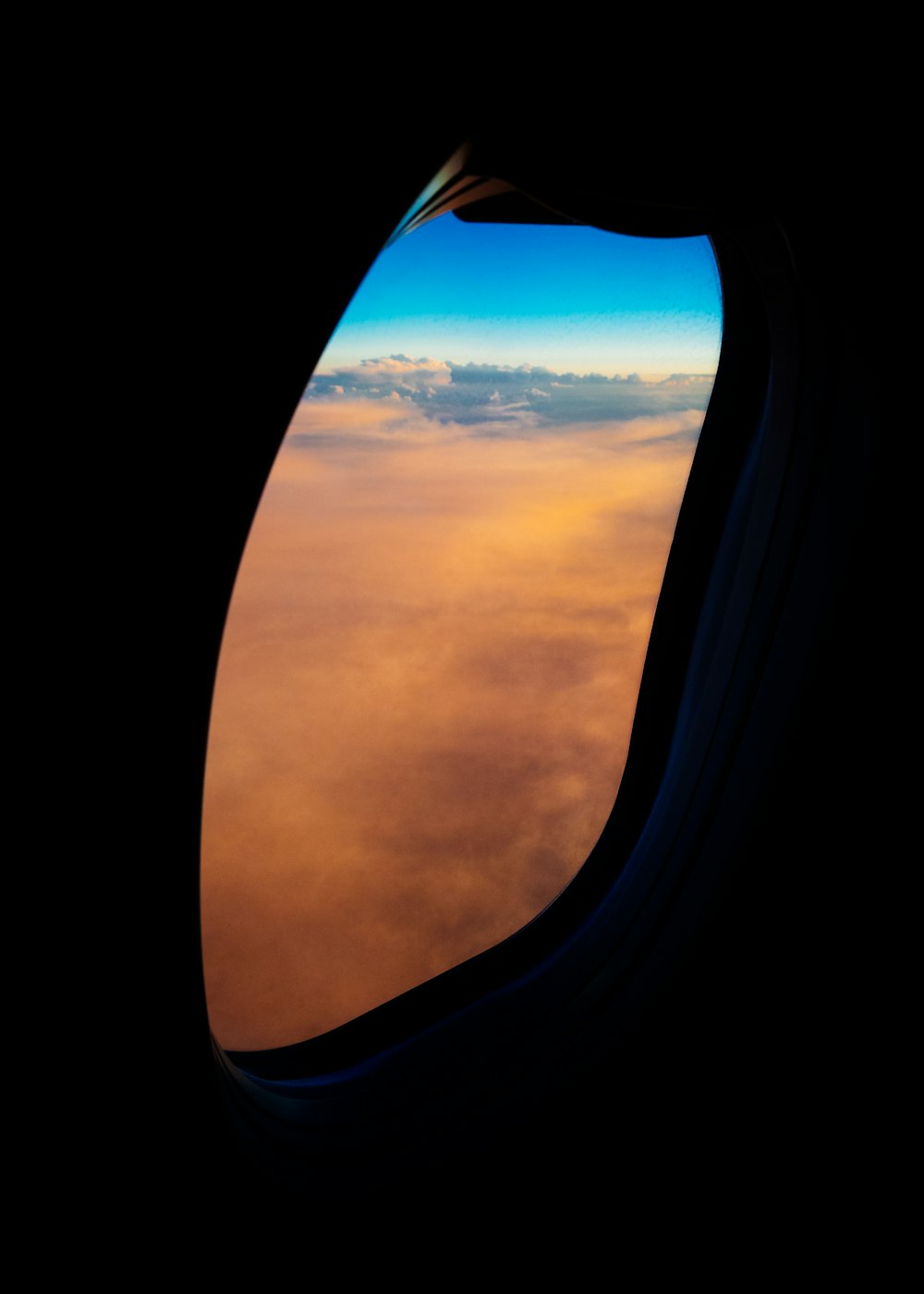 Ventana del avión con vistas a las nubes anaranjadas durante el día