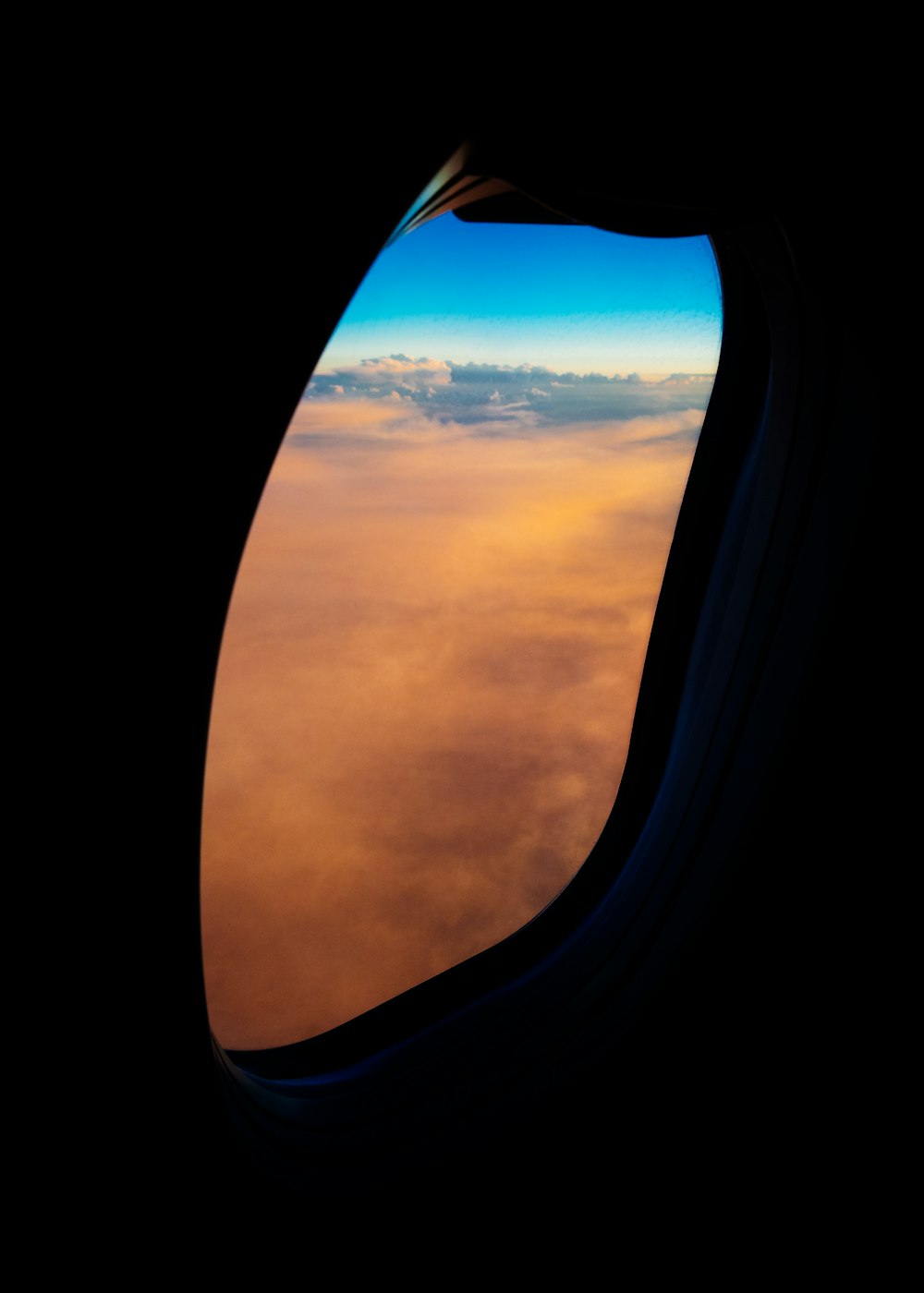 낮에 주황색 구름이 내려다 보이는 항공기 창