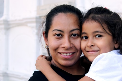 A mother and daughter sharing a warm embrace while choosing clothes together.