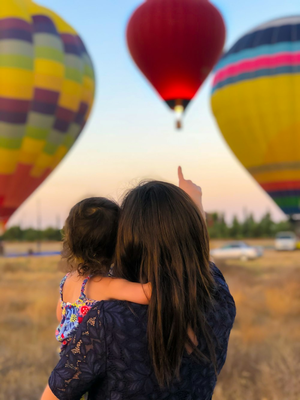 woman carrying toddler point at hot air balloon