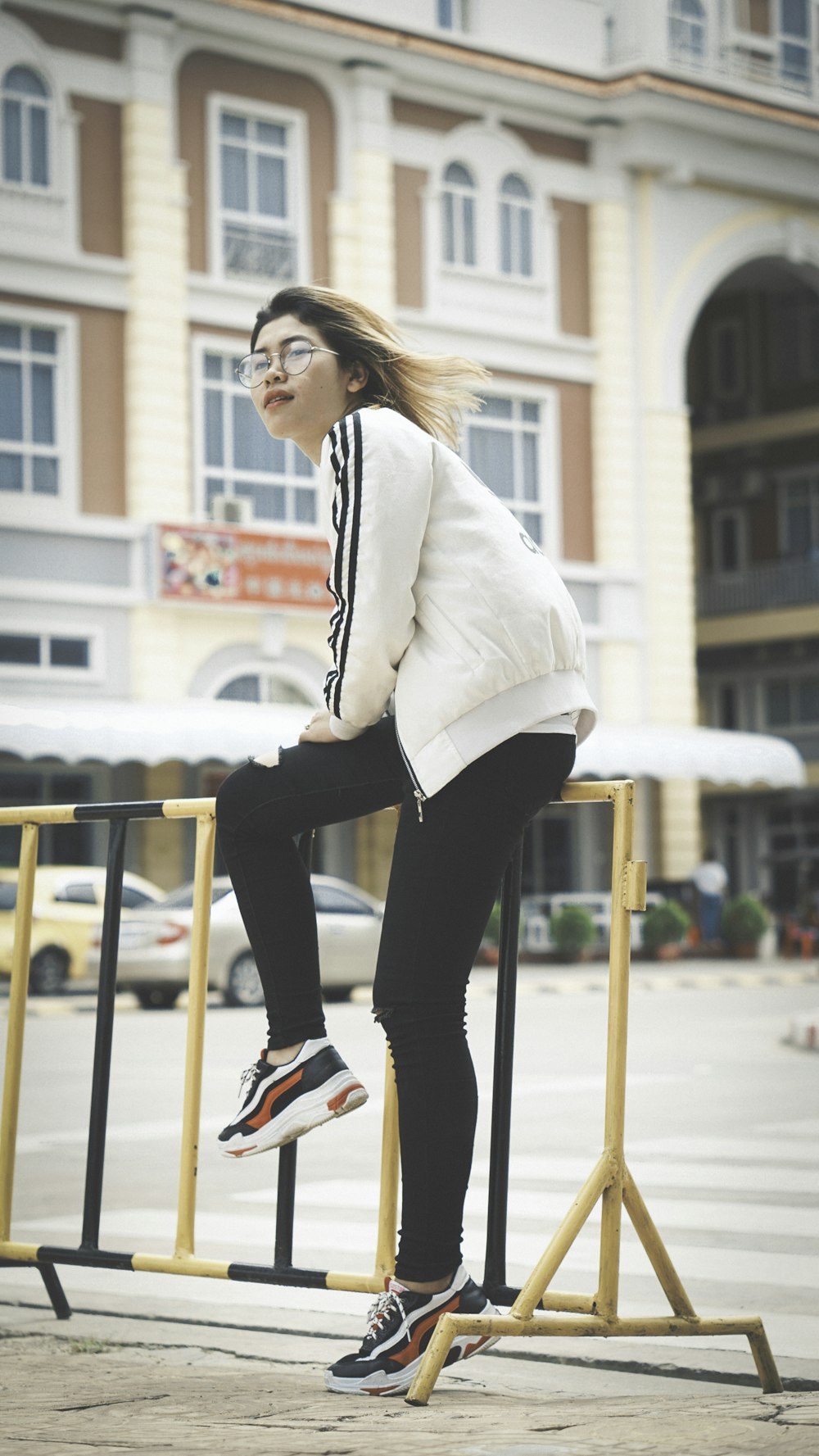 woman sitting on yellow and black steel handrail during daytime