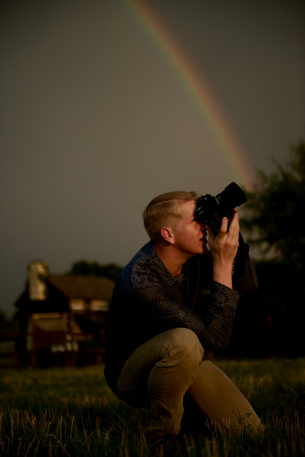 man kneeling while using DSLR camera