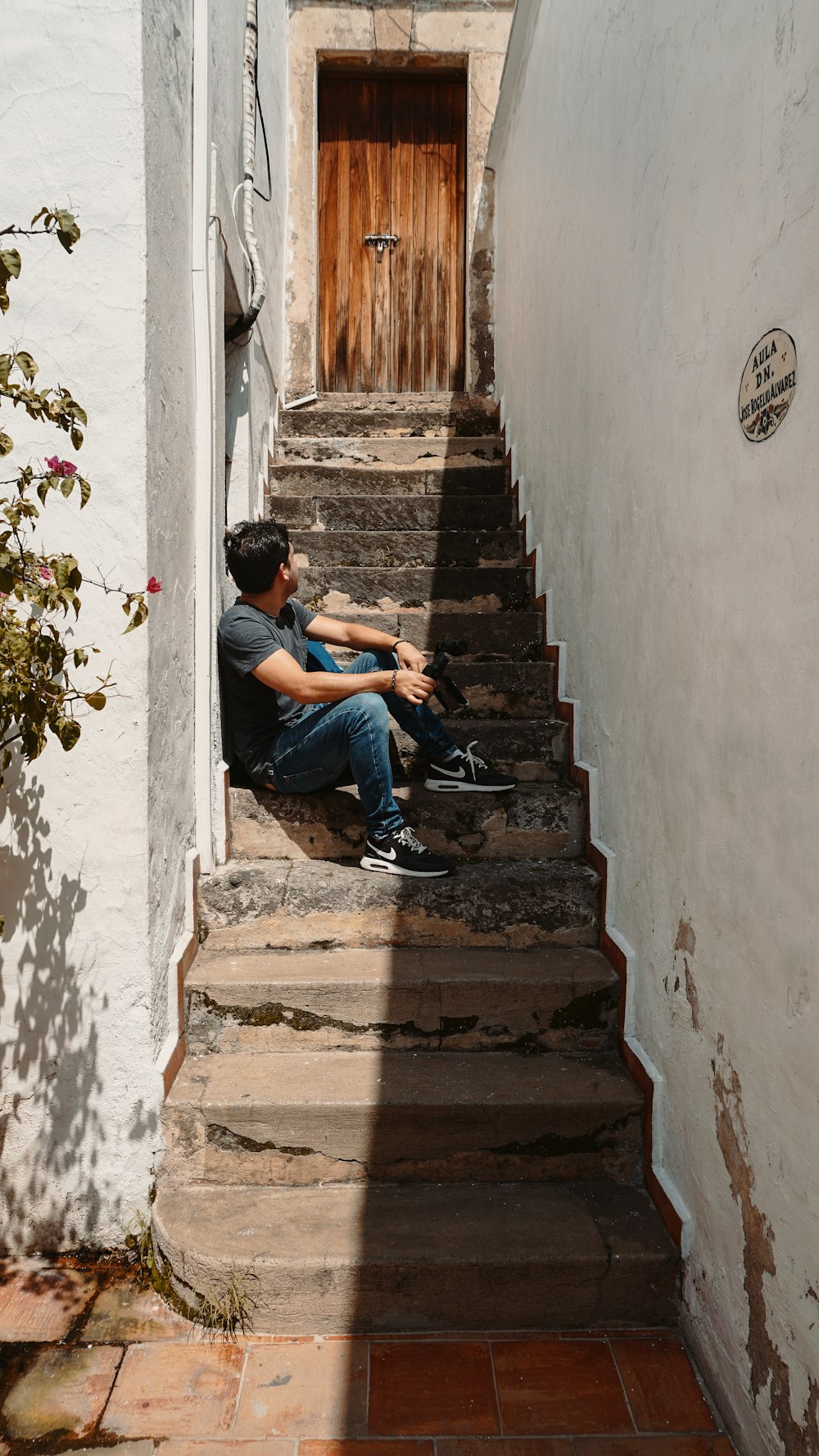 man wearing black crew-neck t-shirt sitting on concrete stairs