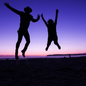 silhouette of two people jumping