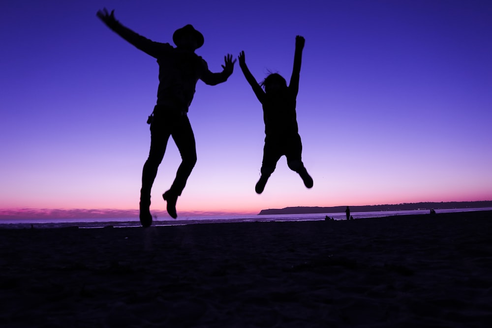 silhouette of two people jumping