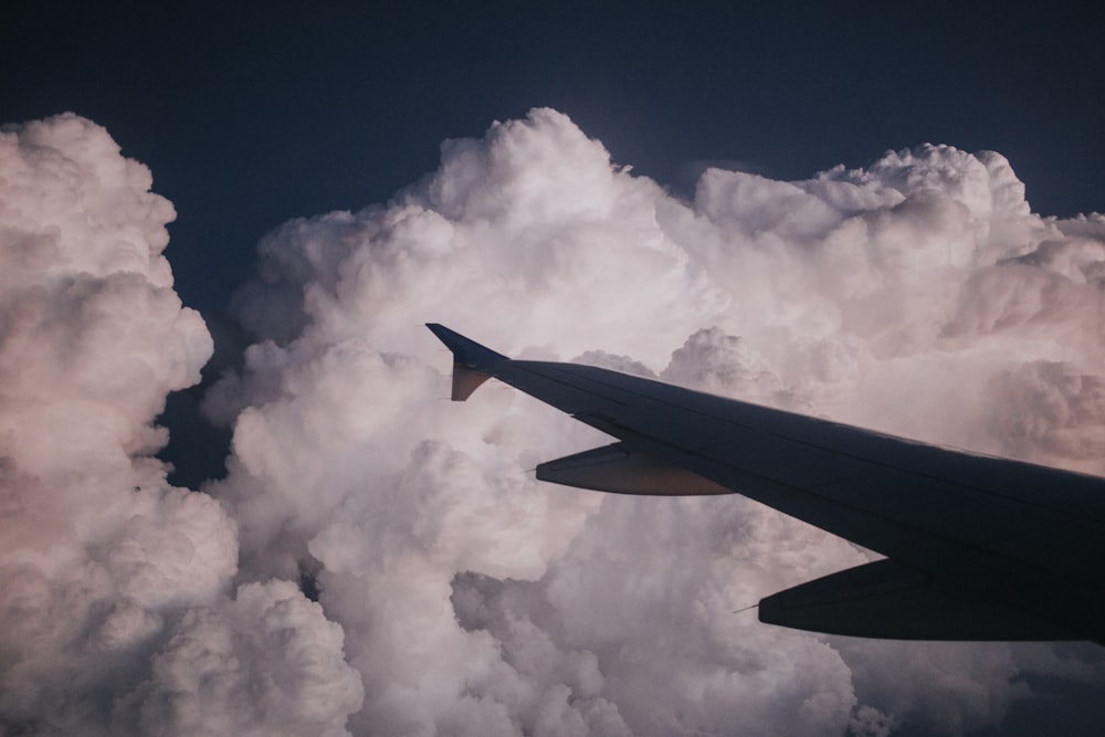 silhouette photography of plane's wing near cumulus clouds