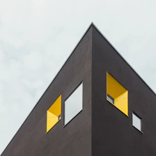 A stark black and yellow brutalist building facade with sharp shadows and geometric lines.