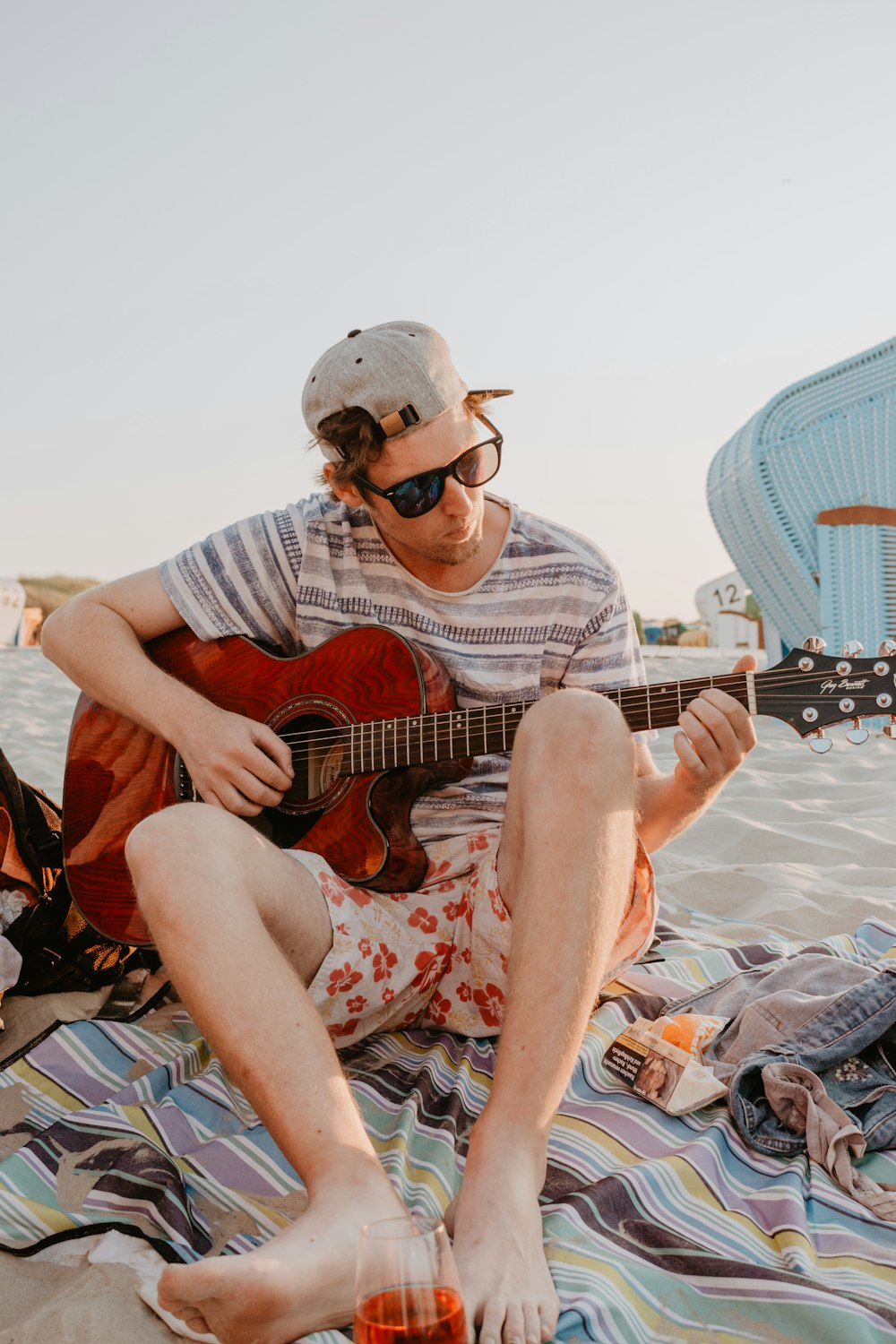 man wearing gray tee shirt holding red guitar