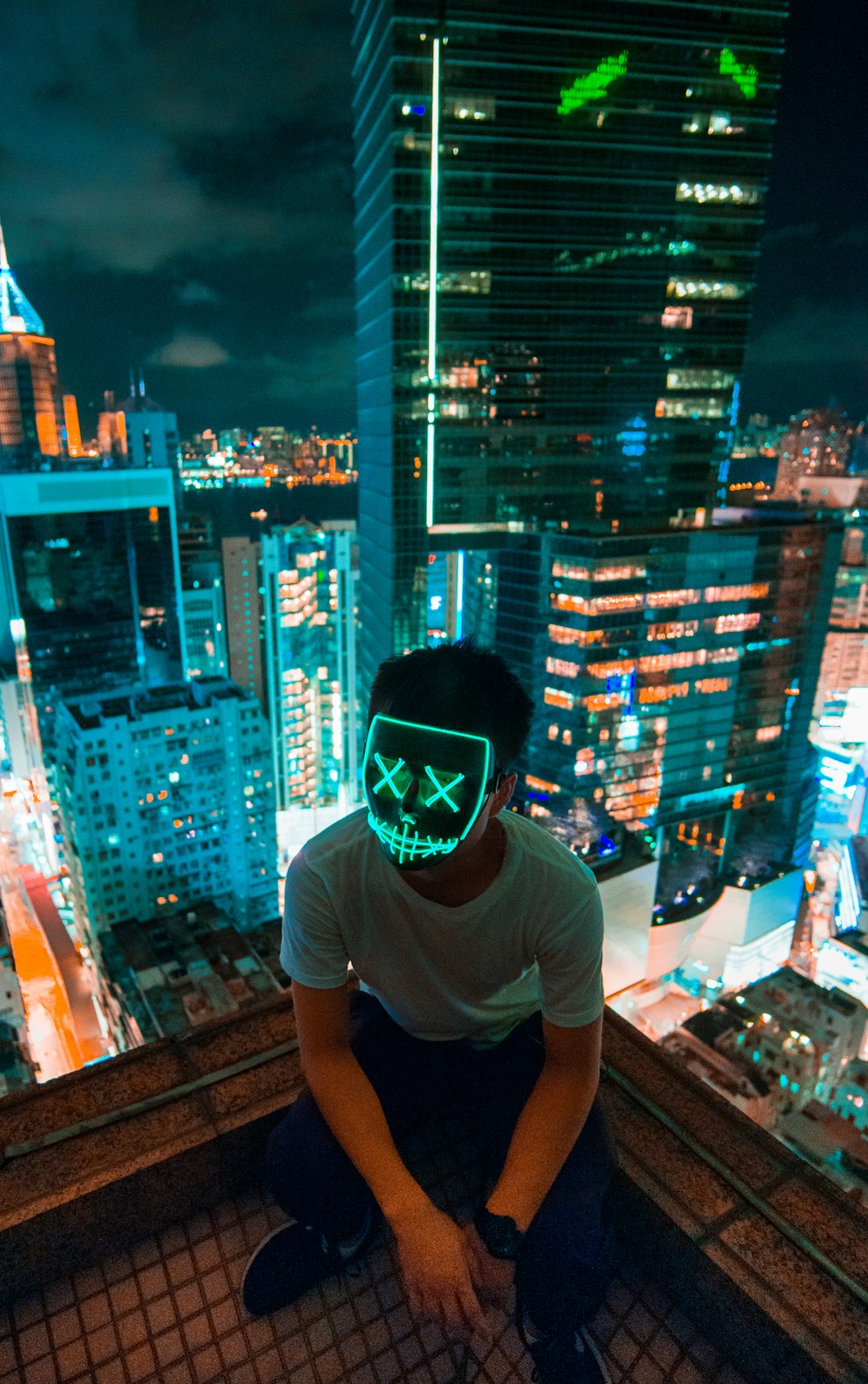 Mann mit Maske sitzt auf dem Dach des Gebäudes