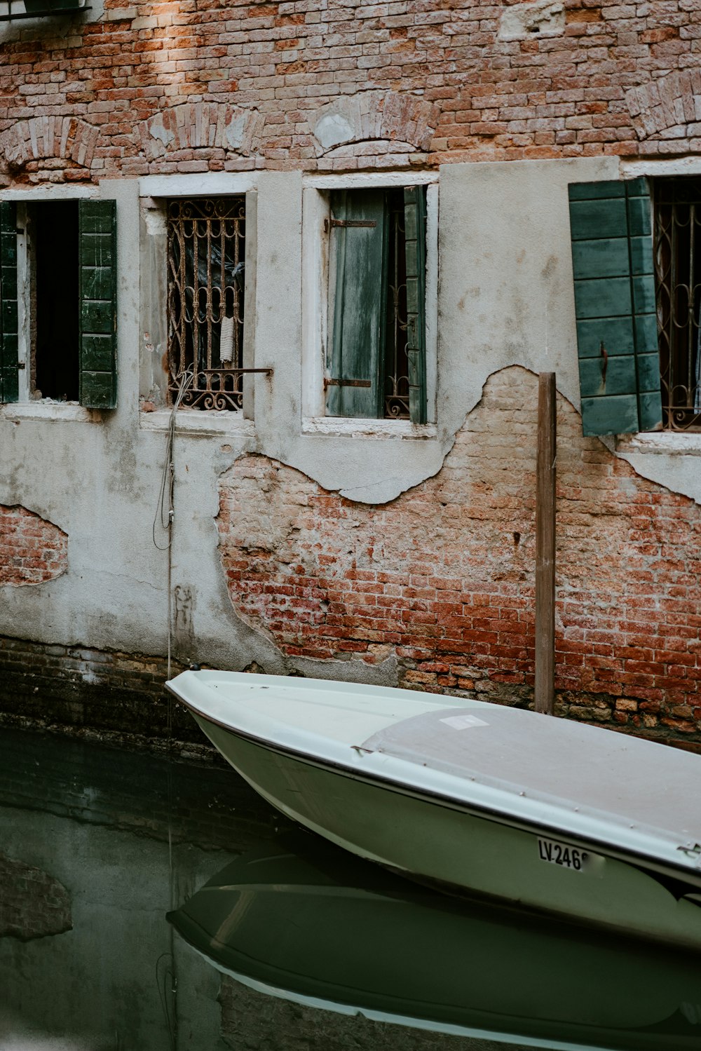 white boat next to brick wall
