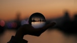 person holding glass ball in selective focus photography