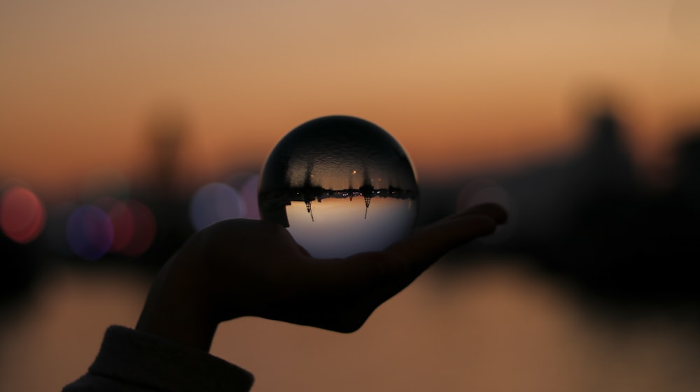 personne tenant une boule de verre dans la photographie sélective