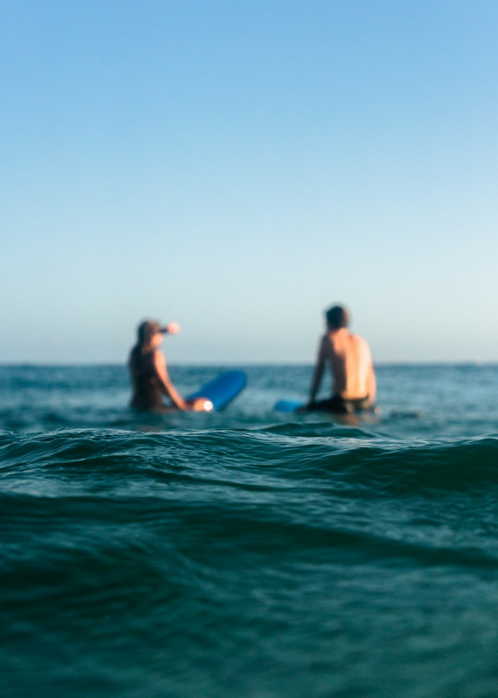 昼間の海に浮かぶ2人のサーファー
