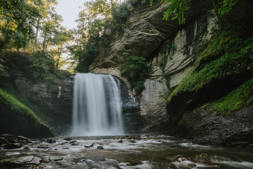 flowing waterfall with rocks and moss on side during daytime