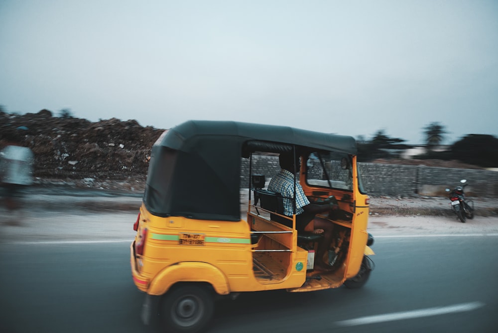 man riding auto rickshaw travelling on road