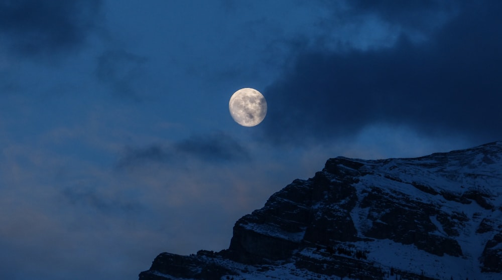 Montanha nevada sob lua cheia durante a noite