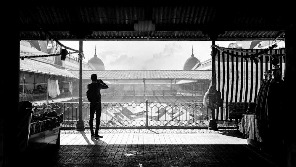 grayscale photography of person standing near house