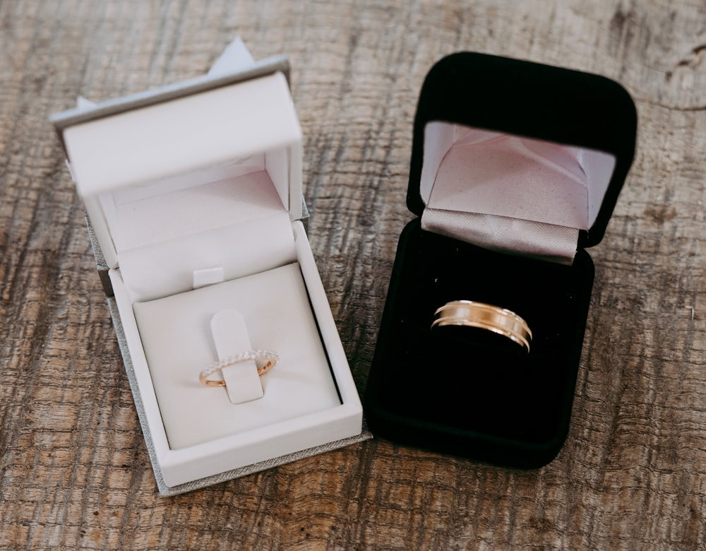 two gold-colored rings inside cases place on brown surface