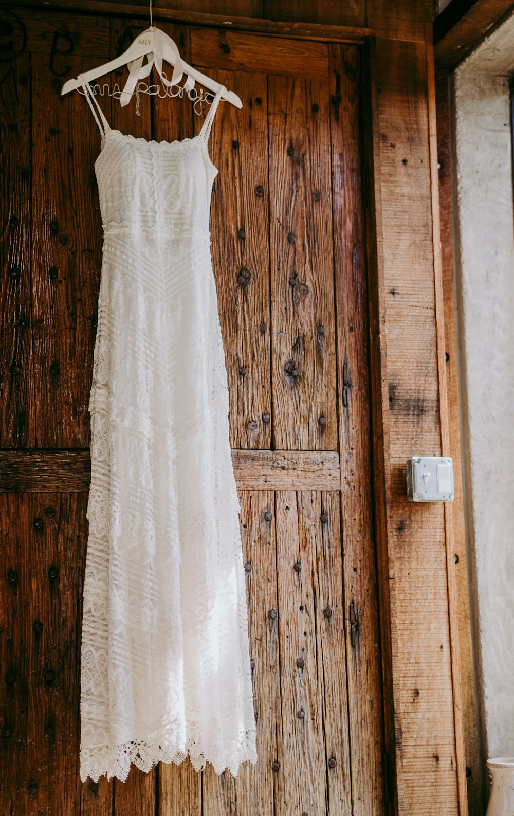 vestido blanco sin mangas cerca de la puerta de madera marrón