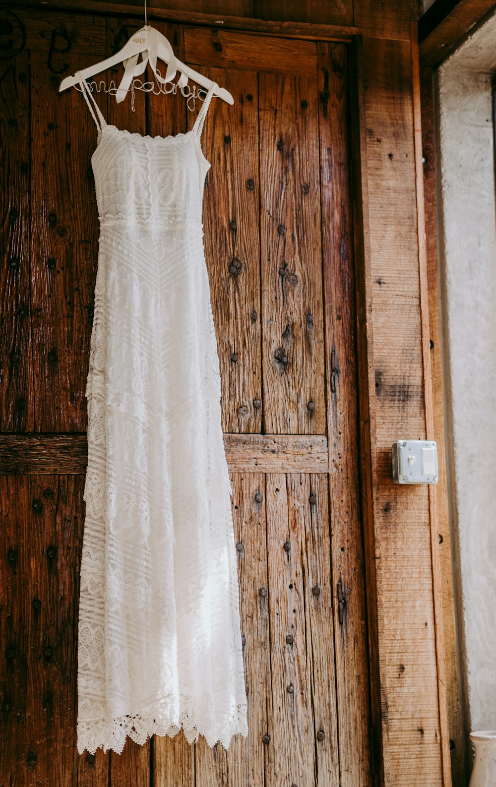 robe blanche sans manches près de la porte en bois marron