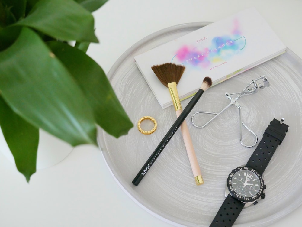 two women's makeup brushes on top of gray wooden surface