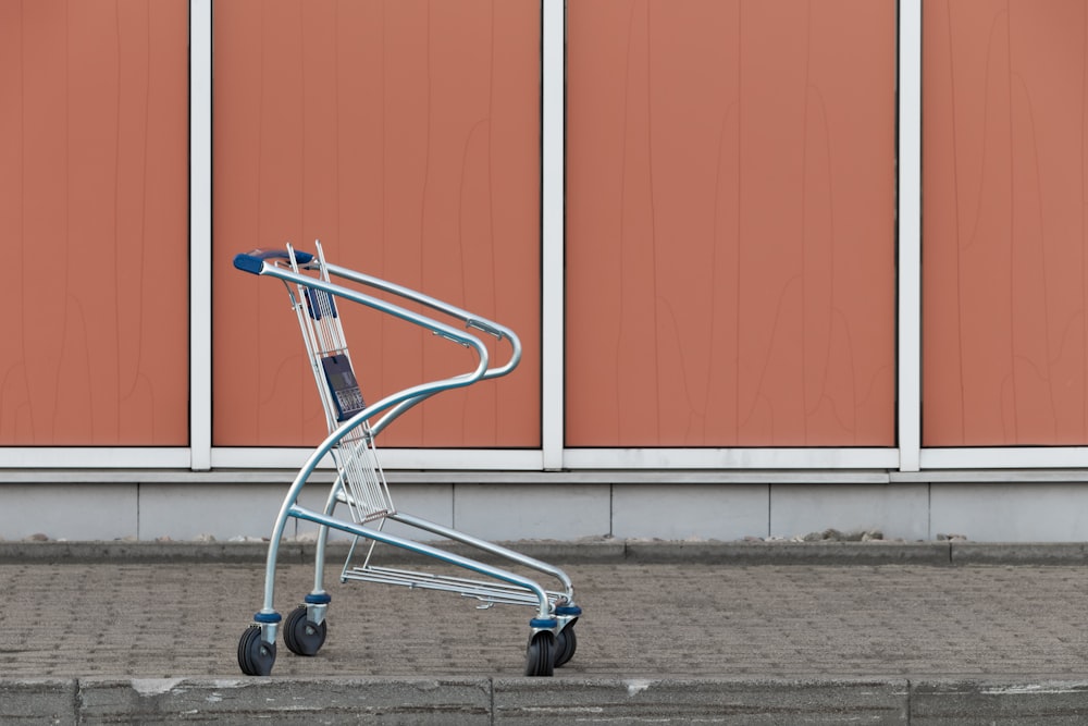 gray shopping cart beside wall